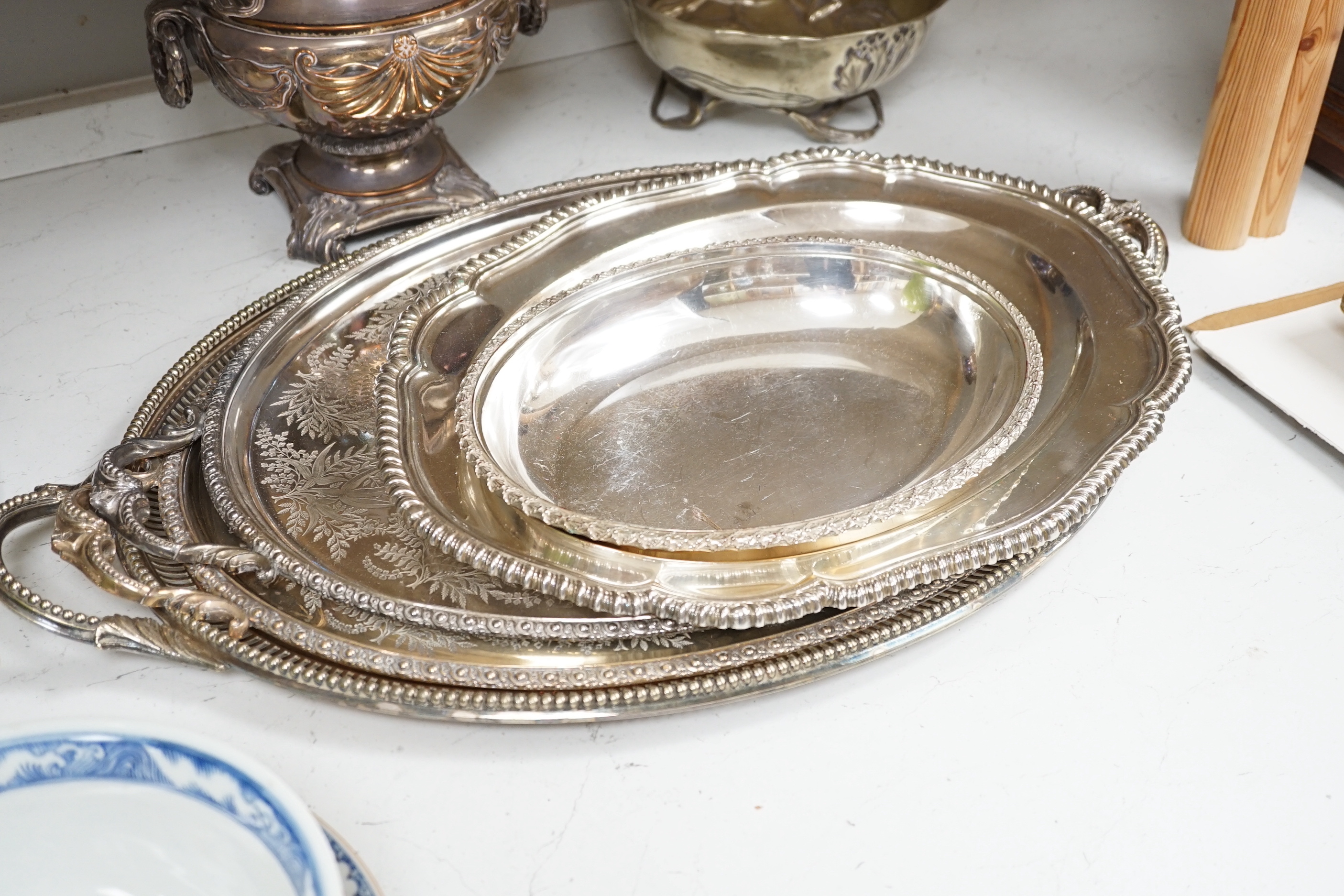 Ten silver plated items, including six good trays, a wine cooler, an Art Nouveau bowl raised on 3 feet, tray of drinking vessels, and a toast rack, largest tray 68cm